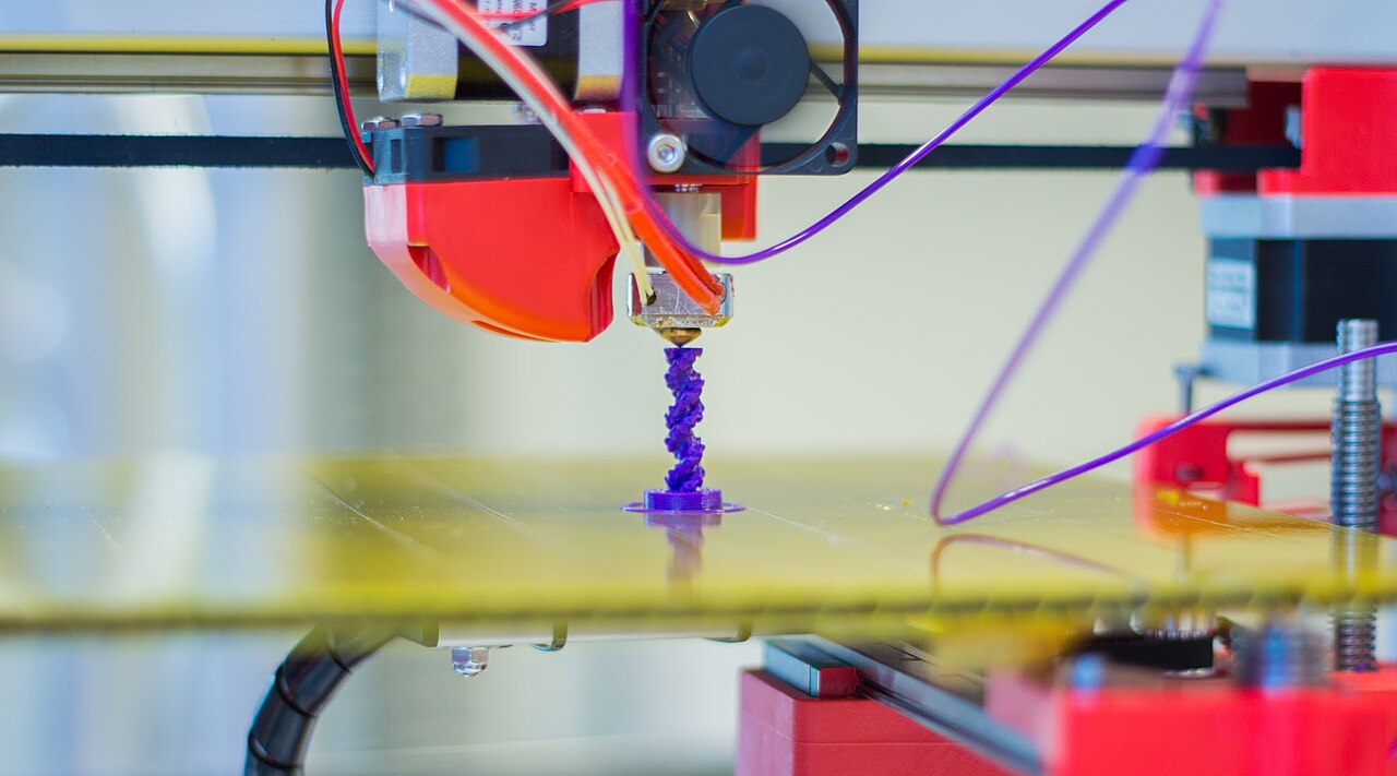 Печатающая головка 3D-принтера наносит фиолетовый пластик на рабочий стол