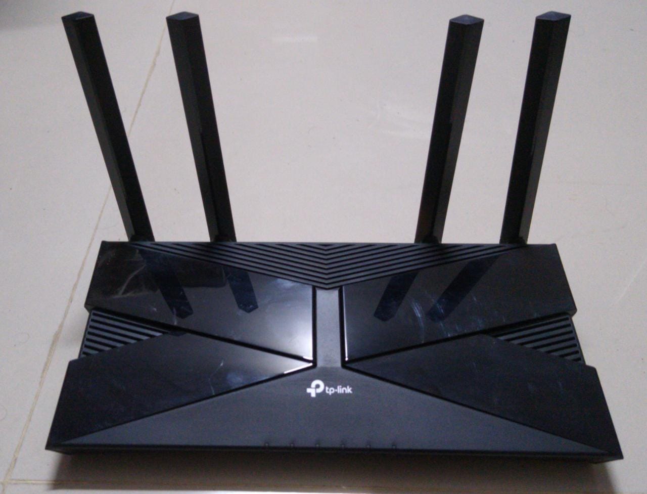 Чёрный Wi-Fi роутер с четырьмя антеннами стоит на светлом полу